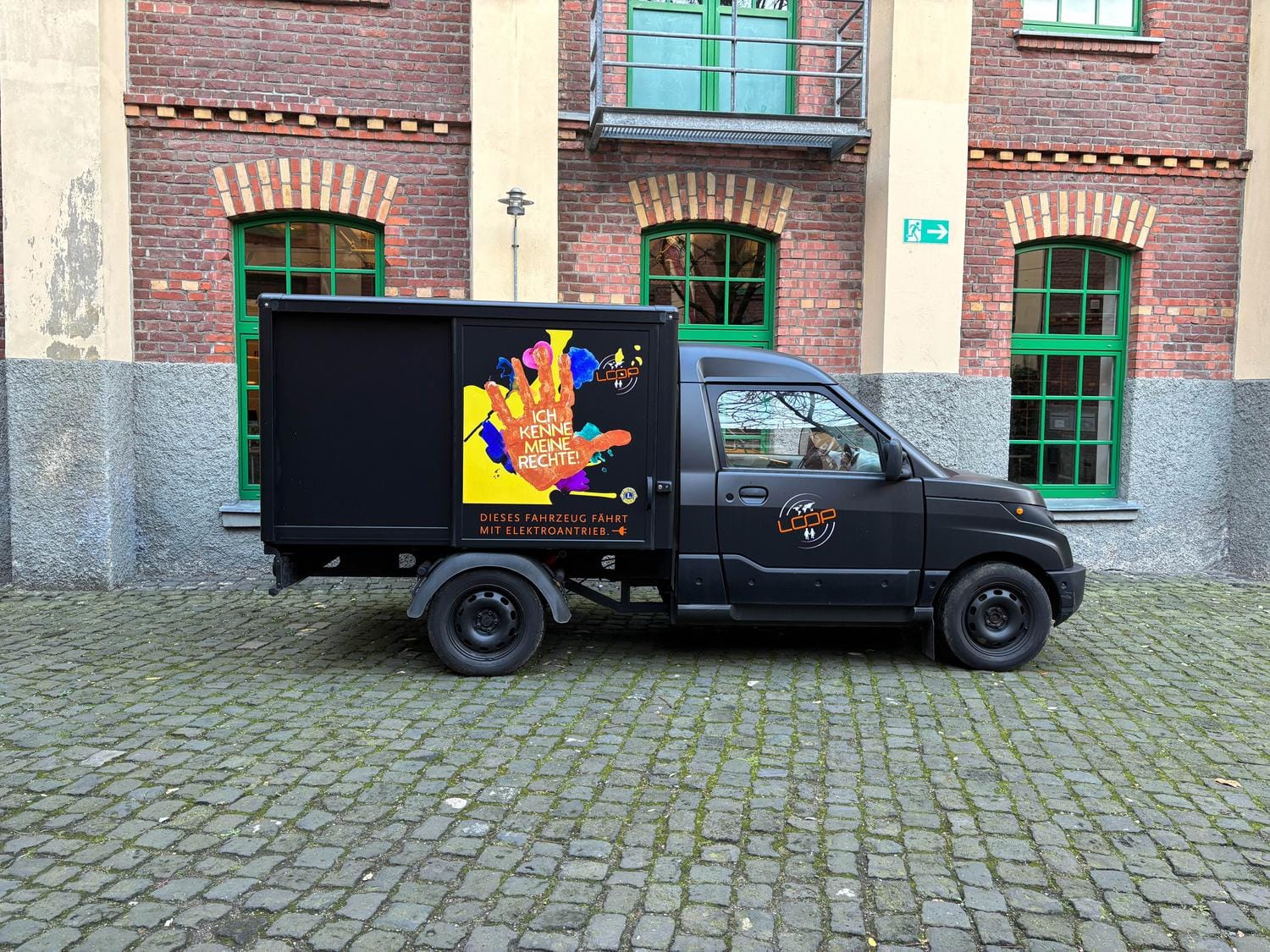Ein Fahrzeug mit aufgebrachtem Vereinslogo steht vor einem Haus