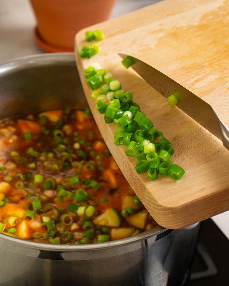 Dieses Bild zeigt wie die Lauchzwiebeln zur Suppe hinzugegeben werden.