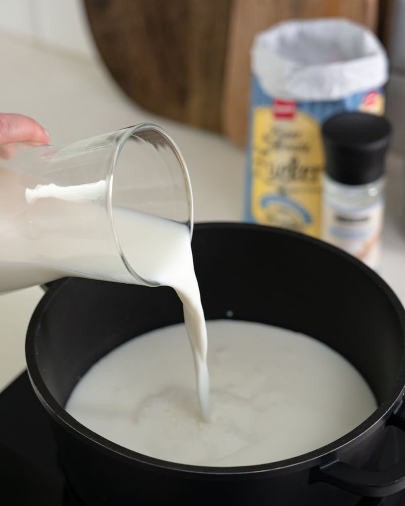 Das Bild zeigt wie Milch in einen Topf gegeben wird.