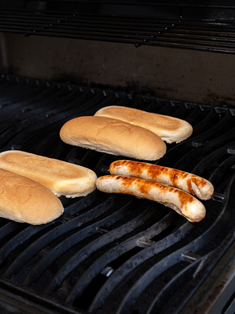Dieses Bild zeigt die Rostbratwürste und die Brötchen auf dem Grill.