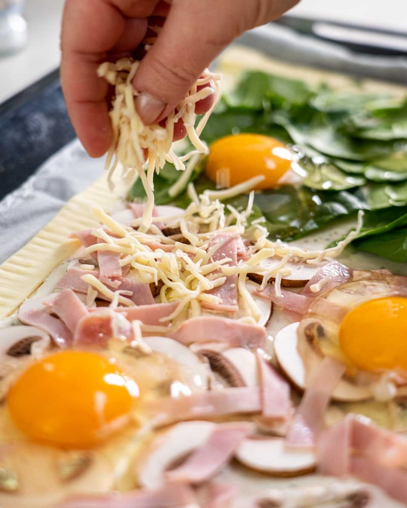 Auf diesem Bild siehst du wie die Pizza mit Käse belegt wird.