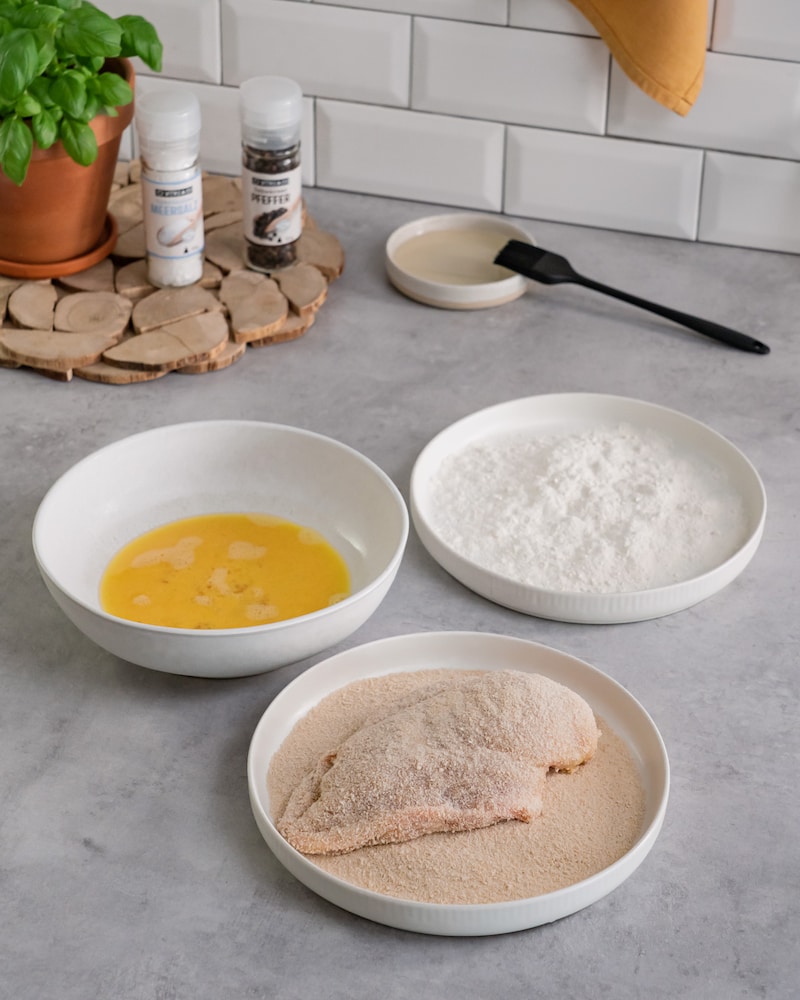 Dieses Bild zeigt, wie die Hähnchenbrust paniert wird.