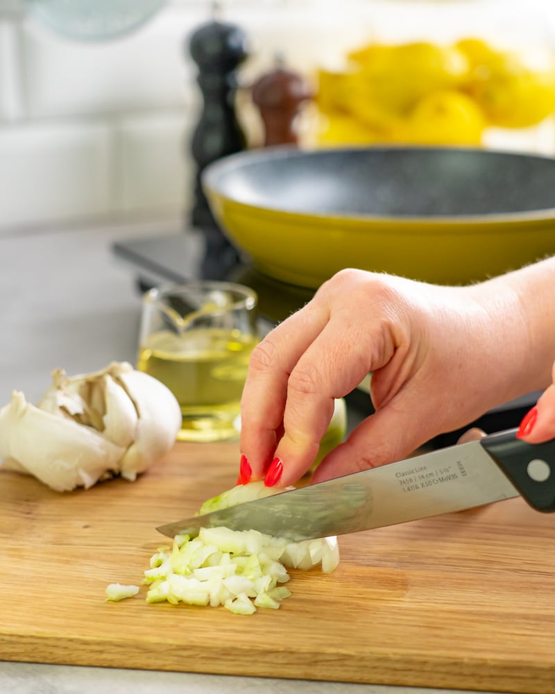 Dieses Bild zeigt wie die Zwiebeln und Knoblauch fein gehackt werden.
