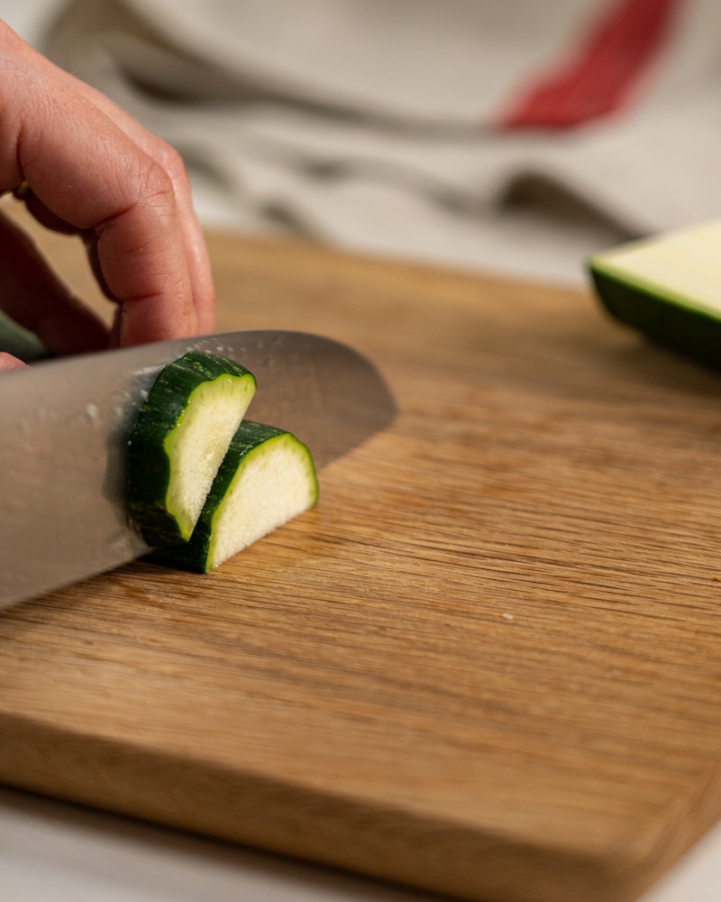 Auf diesem Bild siehst du wie eine Zucchini geschnitten wird.