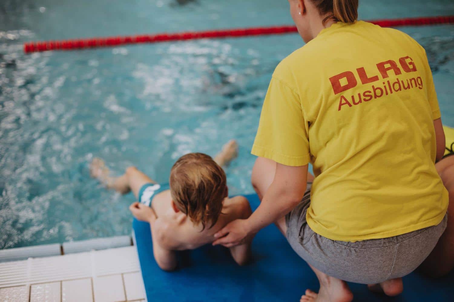 Ein Vereinsmitglied bringt einem Kind das Schwimmen bei