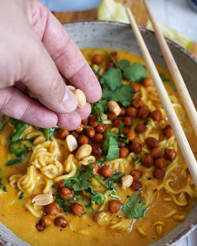 Dieses Bild zeigt, wie die Suppe mit Erdnüssen garniert wird.