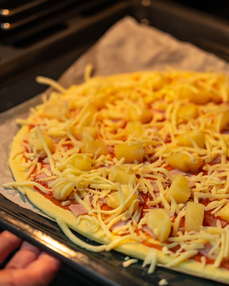 Dieses Bild zeigt wie die Pizza in den Ofen gegeben wird.
