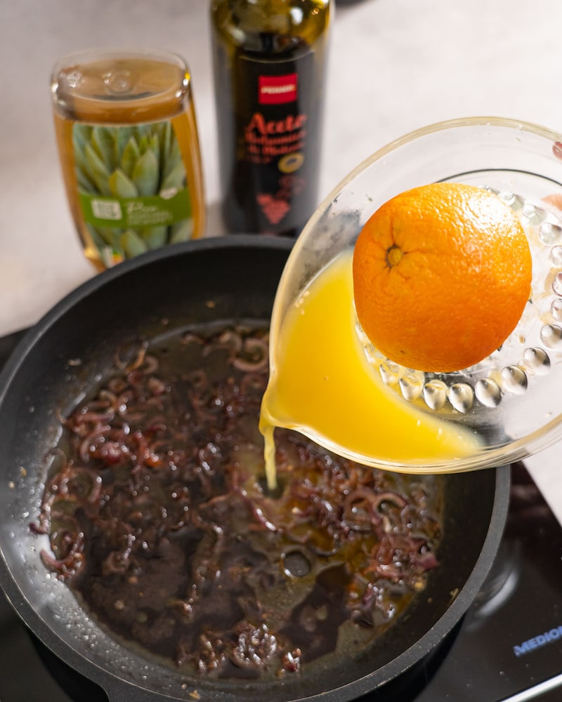 Orangensaft wird aus der Presse zu den Zwiebeln gegeben.