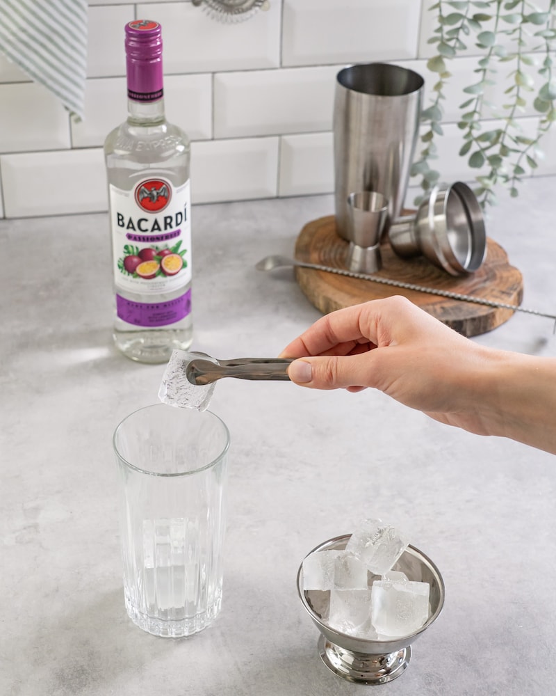 Dieses Bild zeigt wie die Eiswürfel in ein Glas gegeben werden.