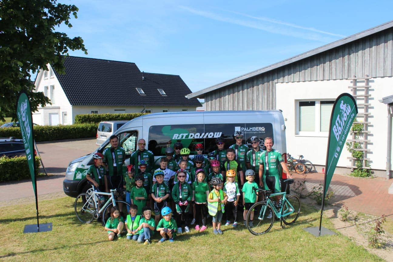 Kinder und Vereinsmitglieder in Ausruestung im Trainingslager laecheln in die Kamera