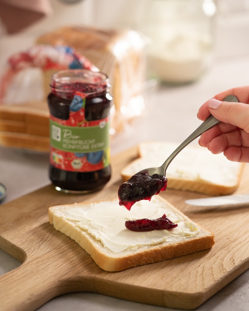 Dieses Bild zeigt wie Konfitüre auf eine Toast-Scheibe geschmiert wird.