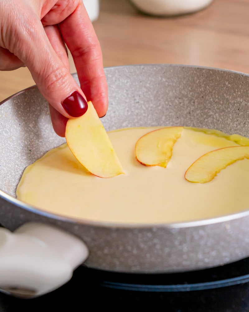 Dieses Bild zeigt wie der Apfel in den Teig in die Pfanne gelegt wird.