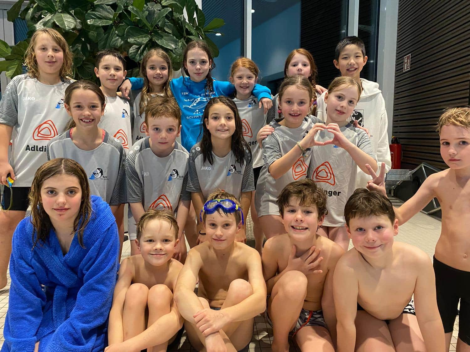 Kinder im Schwimmbad laecheln in die Kamera