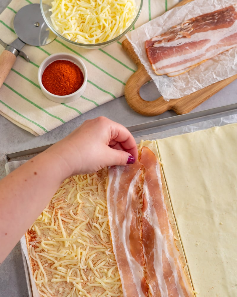 Dieses Bild zeigt das verteilen des Bacon über dem Blätterteig.