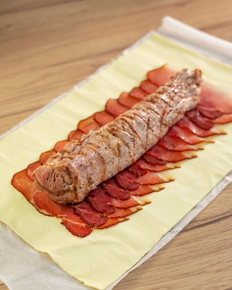 Dieses Bild zeigt, wie das Schweinefilet auf den Blätterteig gelegt wird.