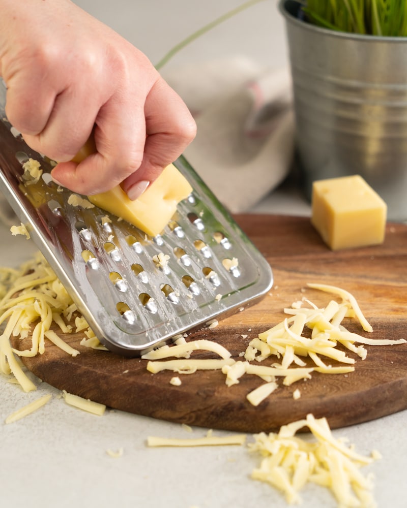 Auf diesem Bild siehst du wie der Käse gerieben wird.