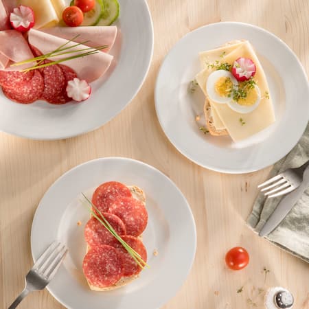 Dieses Bild zeigt ein paar Brötchen mit Wurst und Käse, zusammen mit Schnittlauch und Radieschen.