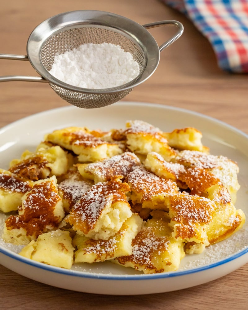 Dieses Bild zeigt wie Puderzucker über den Kaiserschmarrn gegeben wird.