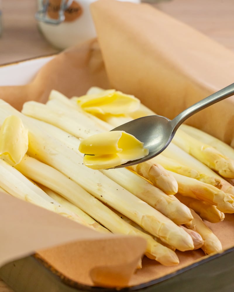 Dieses Bild zeigt wie Butter zum Spargel gegeben wird.