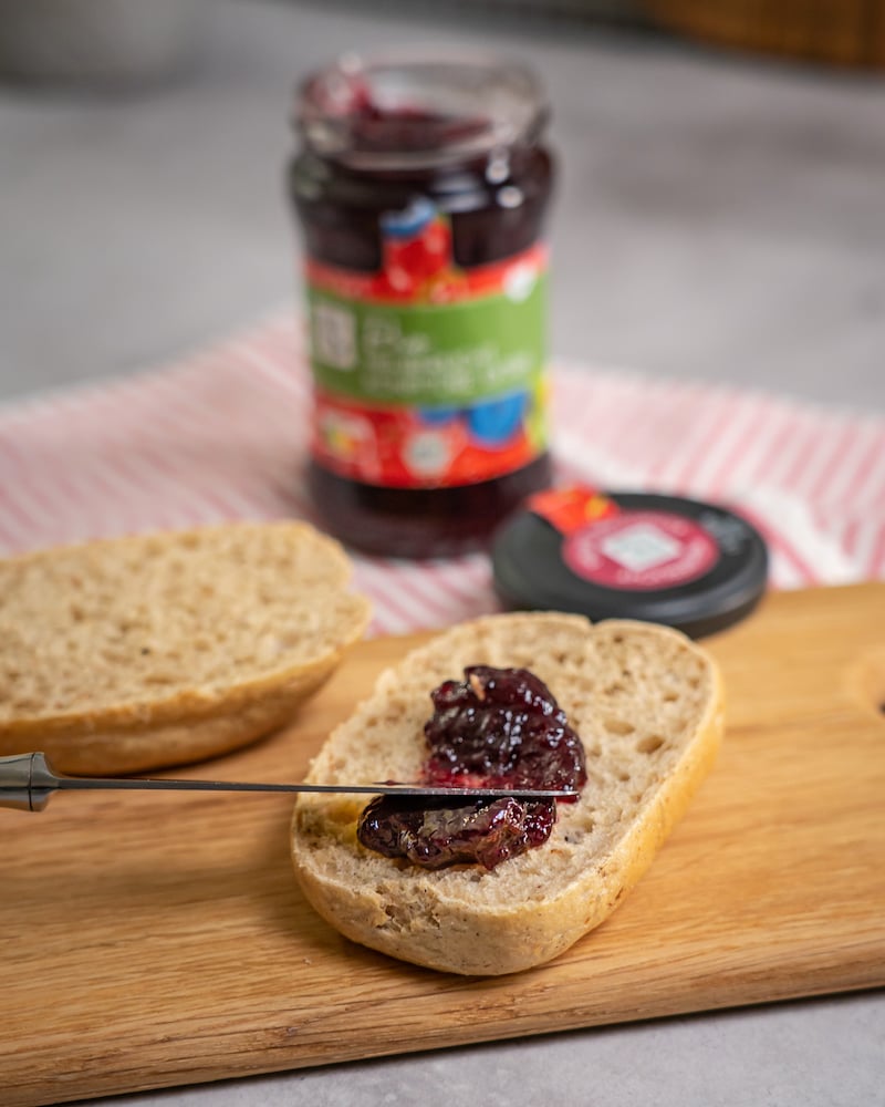 Dieses Bild zeigt wie die Marmelade auf das Brötchen gegeben wird. 