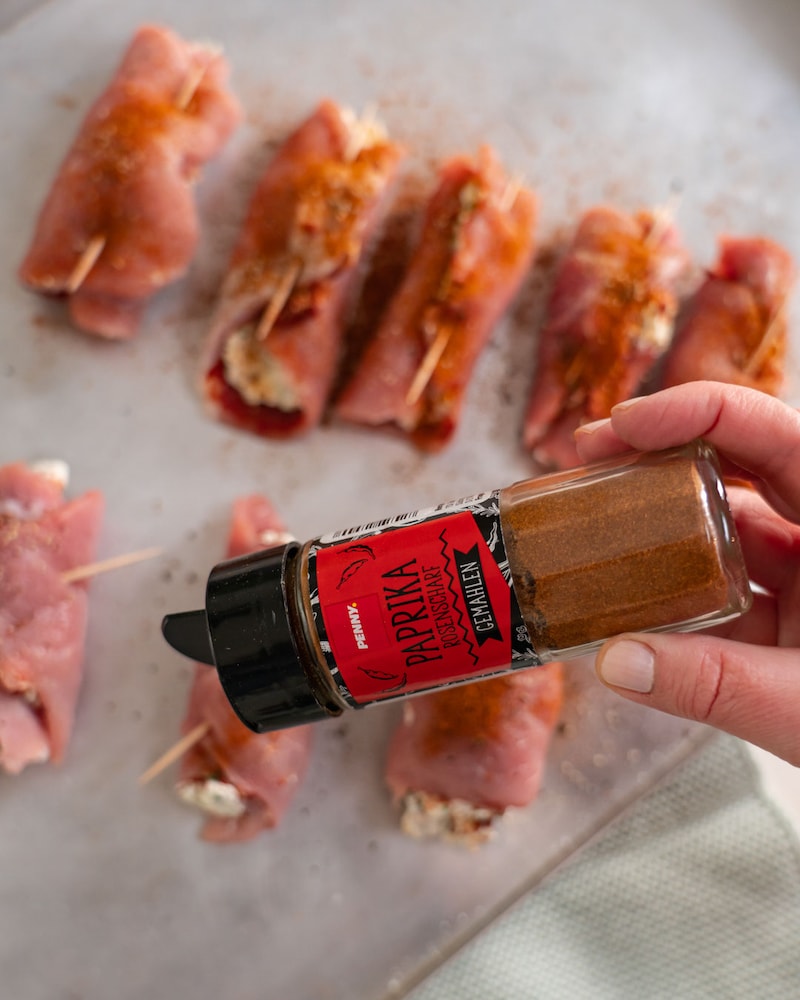 Das Bild zeigt wie die Schweinefilets mit Paprikapulver gewürzt werden.