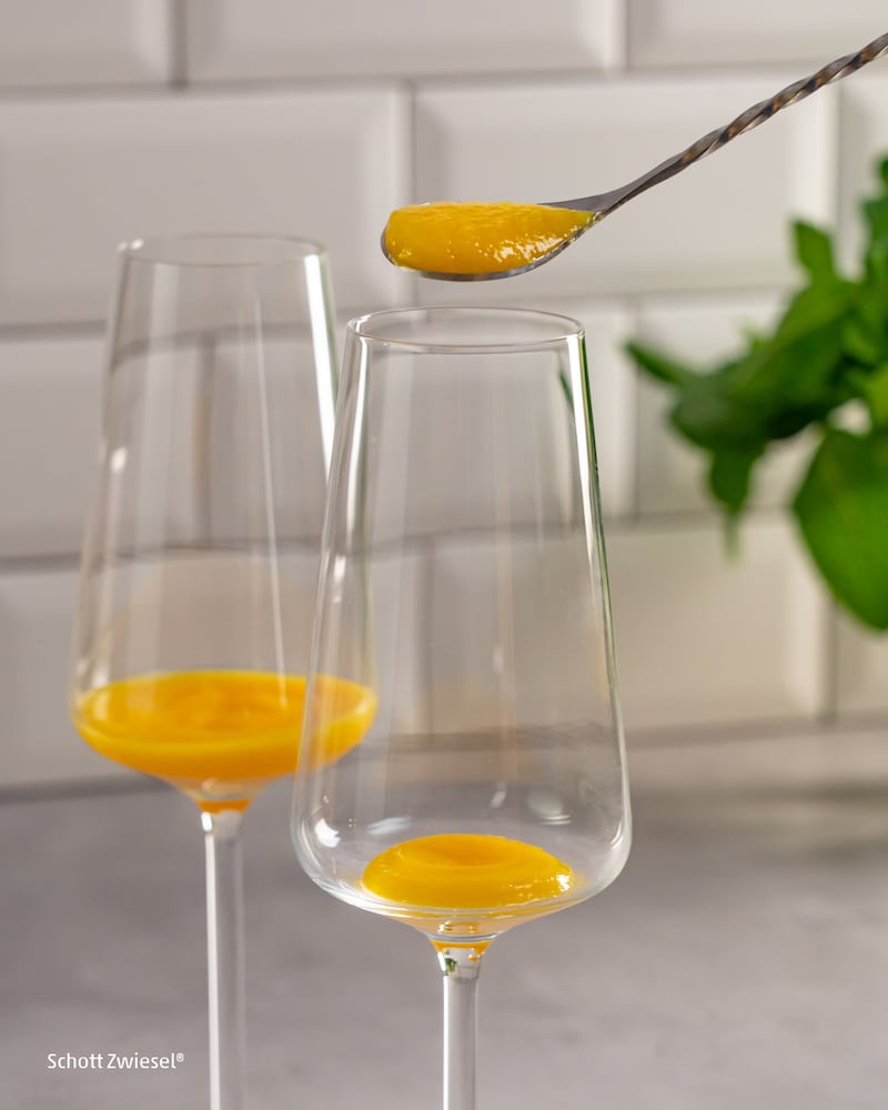 Dieses Bild zeigt wie der pürierte Pfirsich in das Glas gegeben wird.