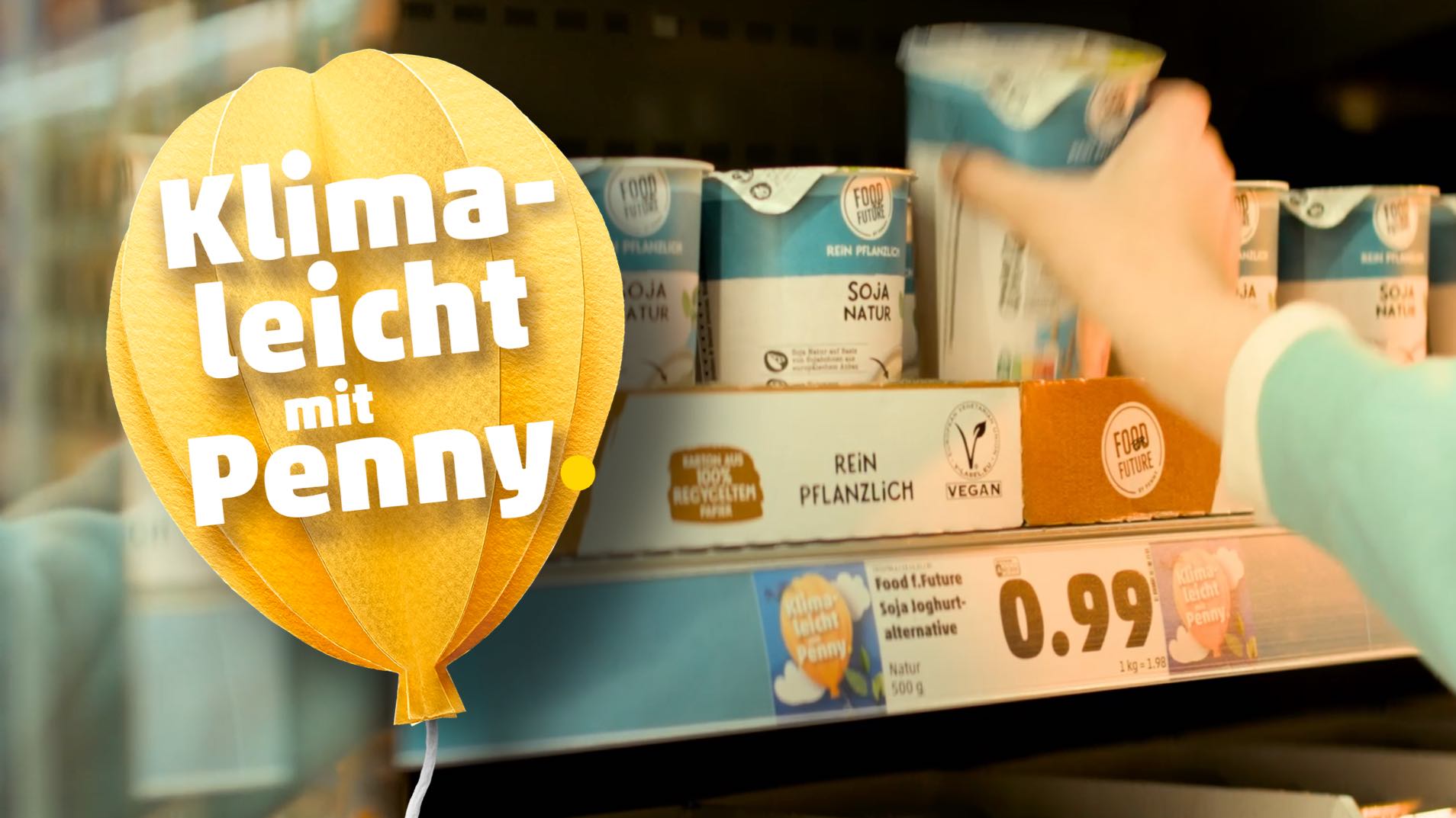 Eine Hand nimmt einen Sojajoghurt aus deinem Regal in einem PENNY Markt.