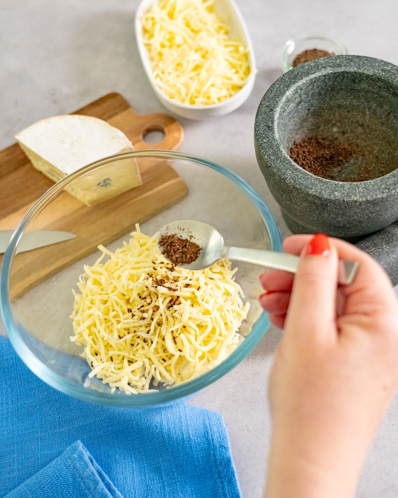 Dieses Bild zeigt wie der Kümmel zu dem Käse gegeben wird.