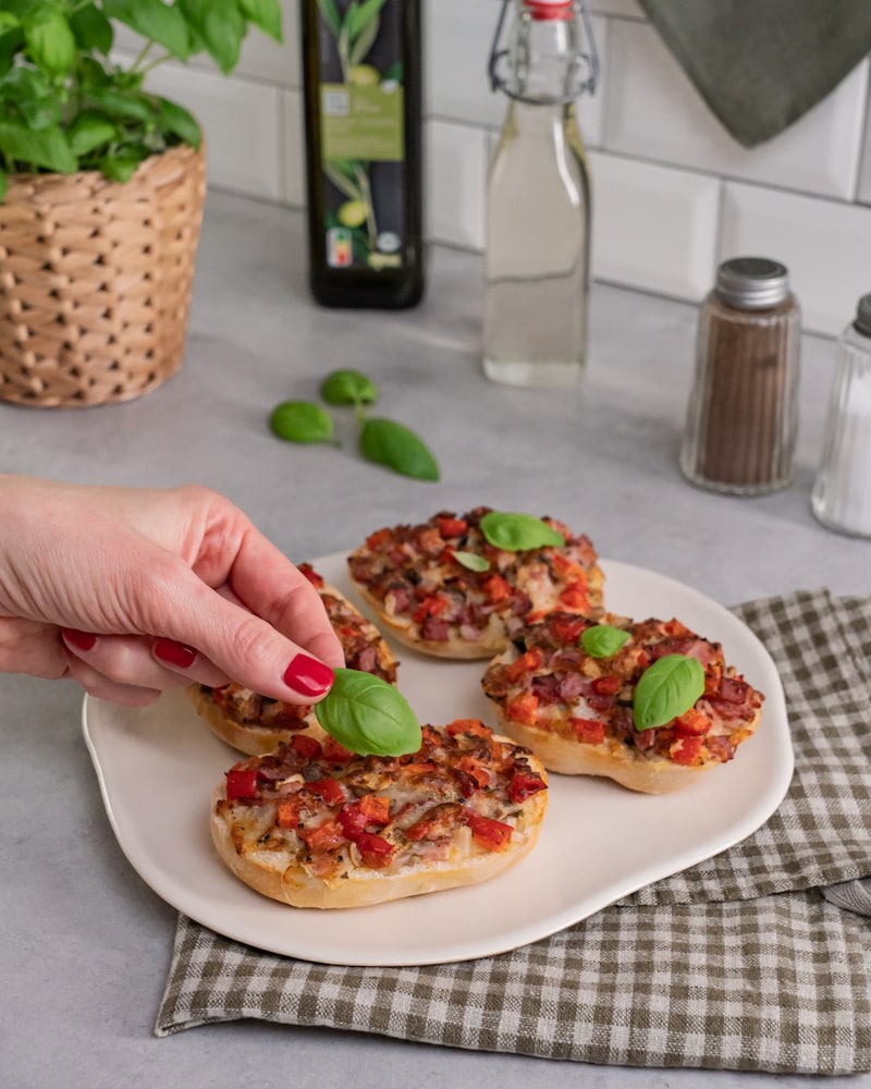 Dieses Bild zeigt wie die Pizzabrötchen garniert werden.