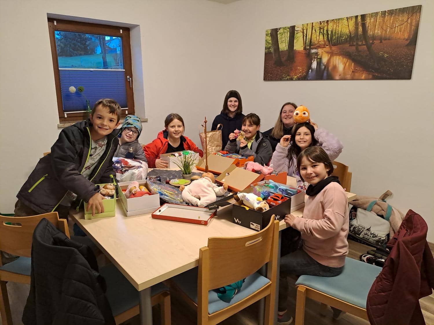 Kinder spielen am Tisch und laecheln in die Kamera