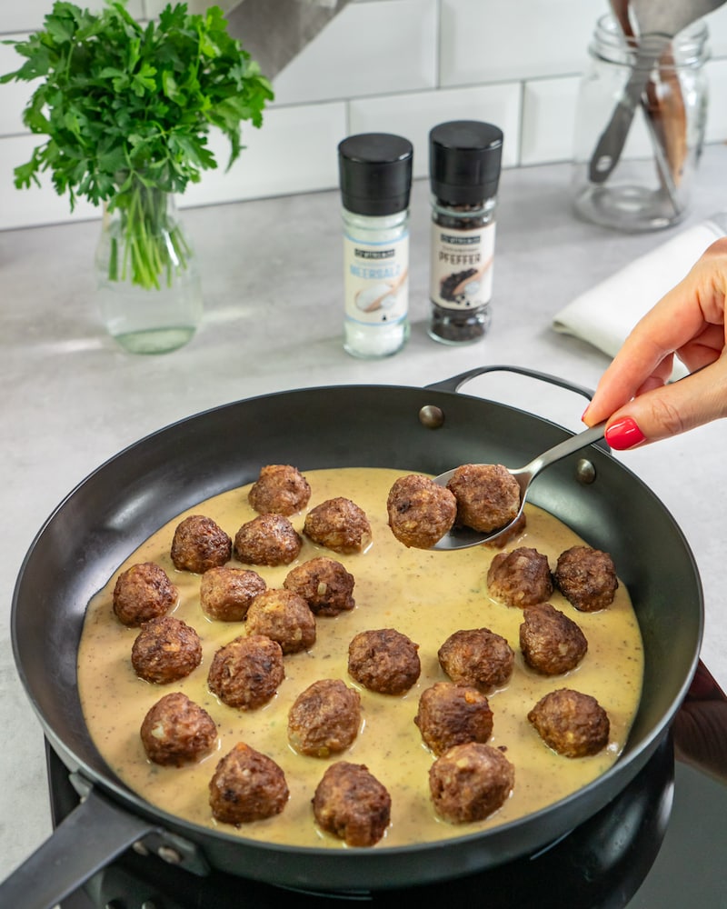 Das Bild zeigt wie die Köttbullar in die Soße gelegt werden.
