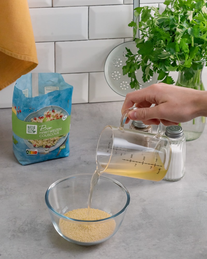 Dieses Bild zeigt wie der Couscous mit Brühe aufgegossen wird.