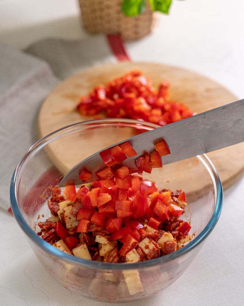 Auf diesem Bild siehst du wie Käse und Paprika vermengt werden.