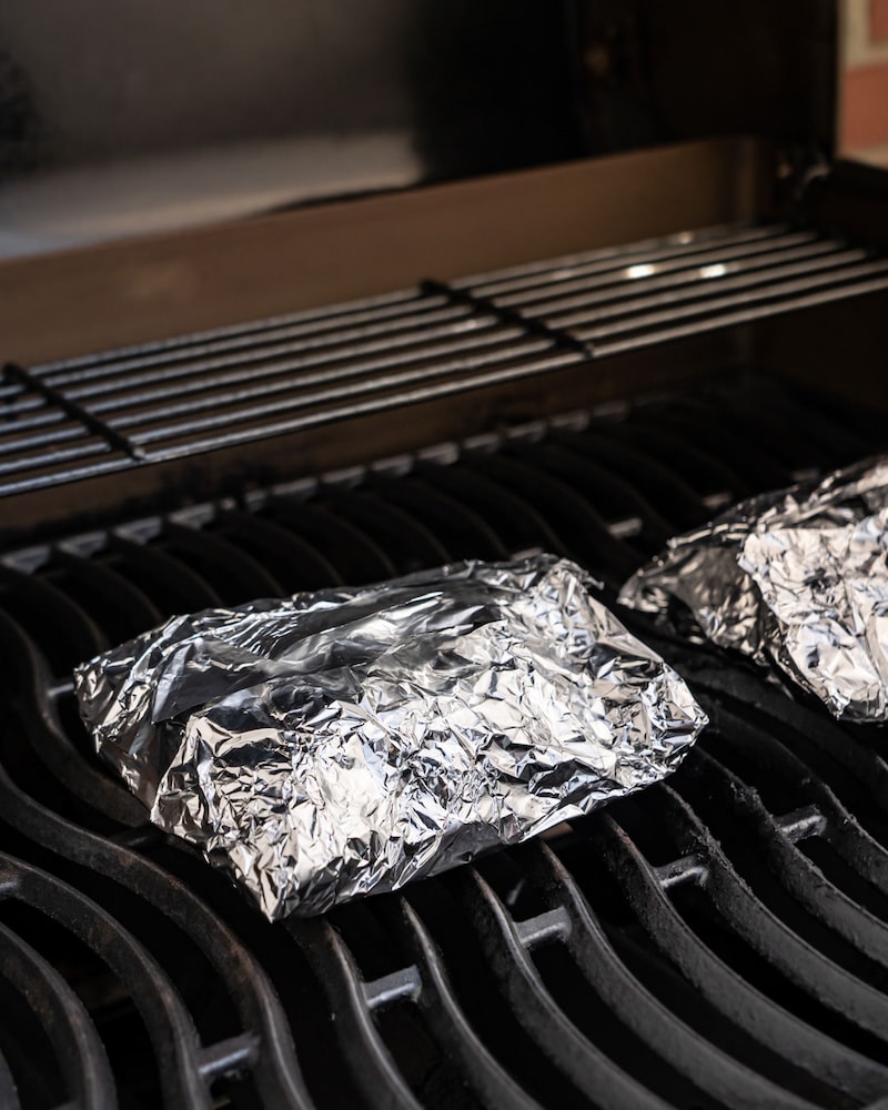 Dieses Bild zeigt wie der Blumenkohl in Aluminiumfolie gegrillt wird.