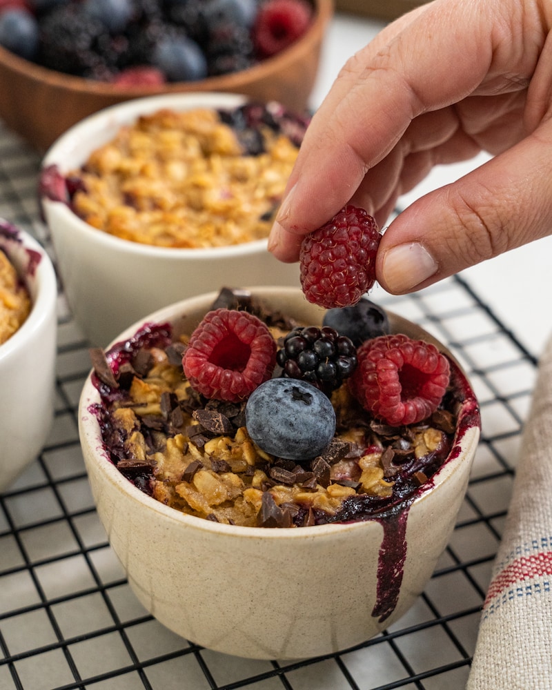 Auf diesem Bild siehst du wie frische Beeren auf den Oats drapiert werden.