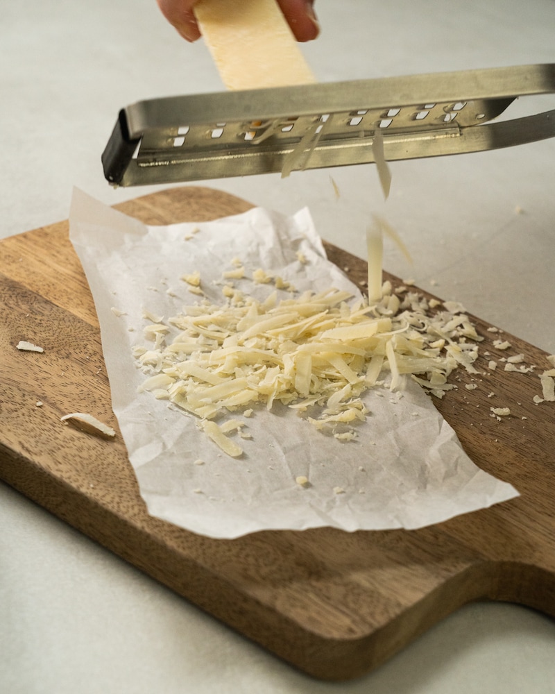 Auf diesem Bild siehst du wie Käse gerieben wird.