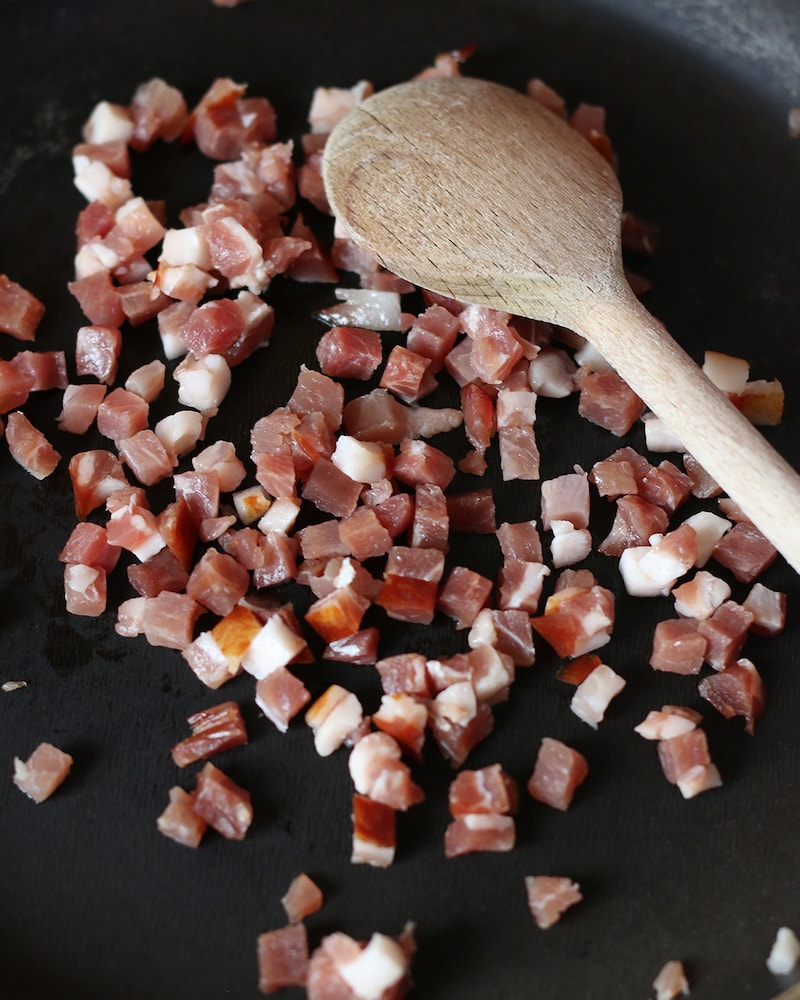 Auf diesem Bild siehst du wie Speck angebraten wird.