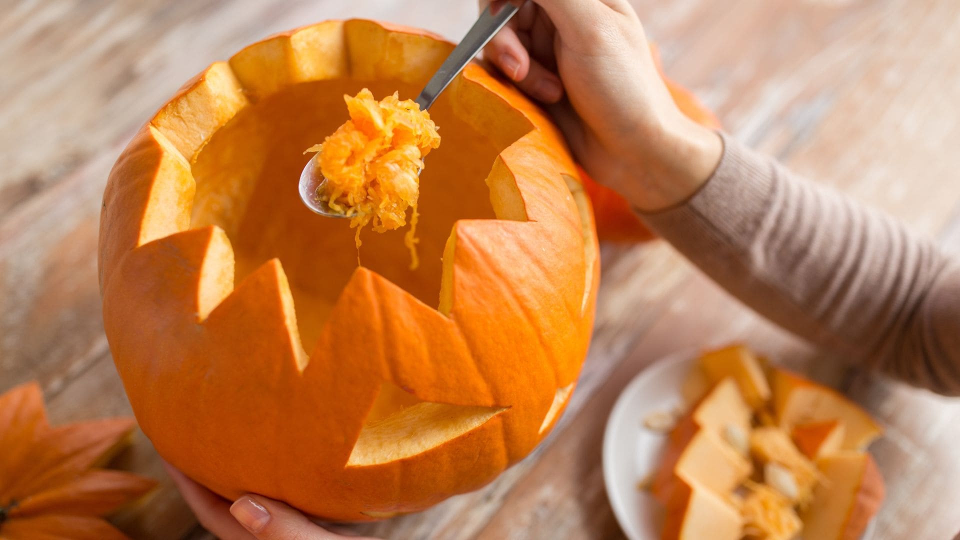 Ein Kürbis wird mit einem Löffel ausgehöhlt