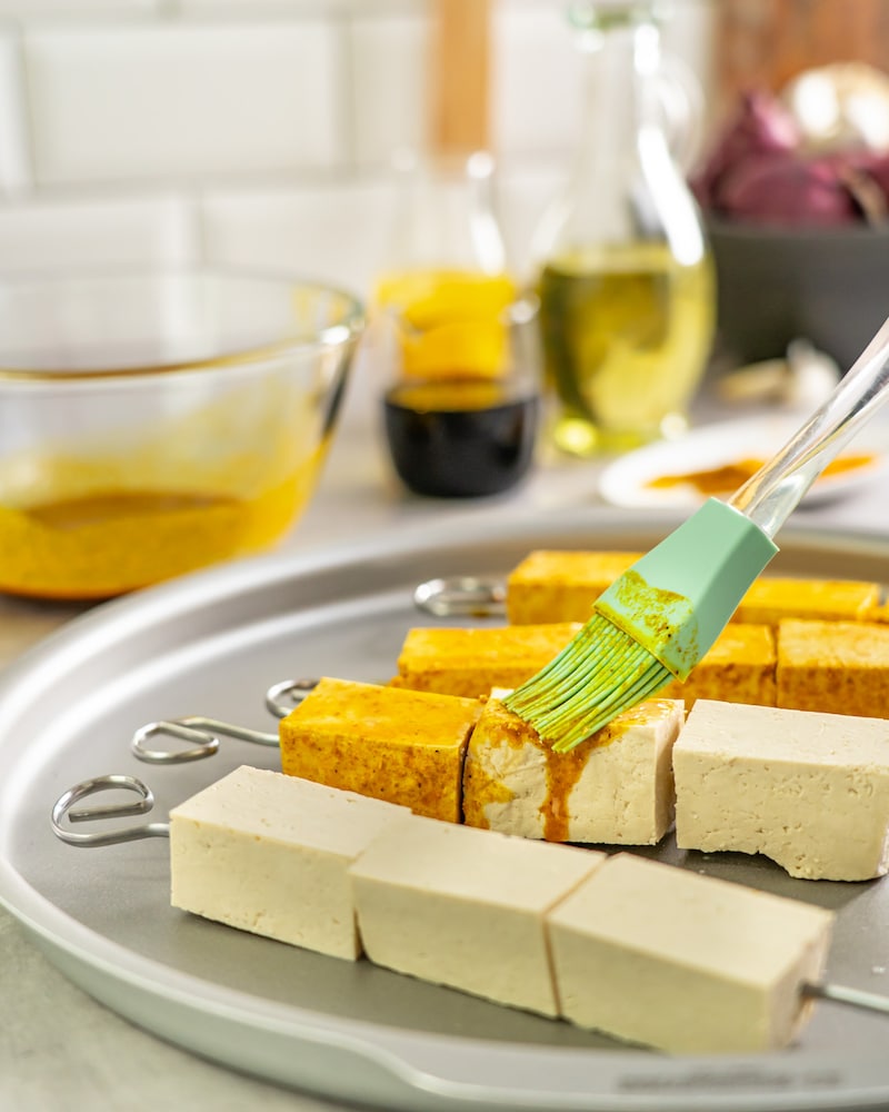 Diese Bild zeigt wie der Tofu mit der Marinade bestrichen wird.