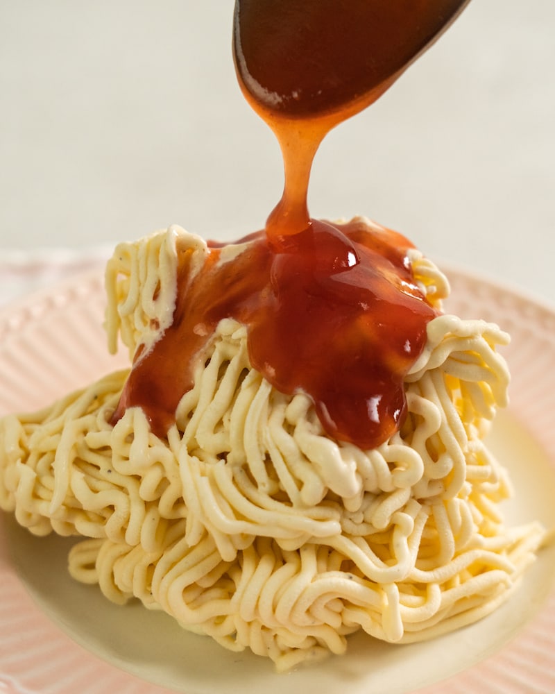 Auf diesem Bild siehst du wie die Erdbeersoße über das Eis gegeben wird.