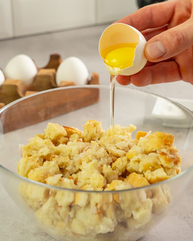 Dieses Bild zeigt wie ein Ei zu den Brötchen gegeben wird.