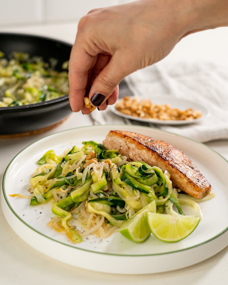 Auf diesem Bild siehst du wie das Lachsfilet mit Erdnüssen garniert wird.