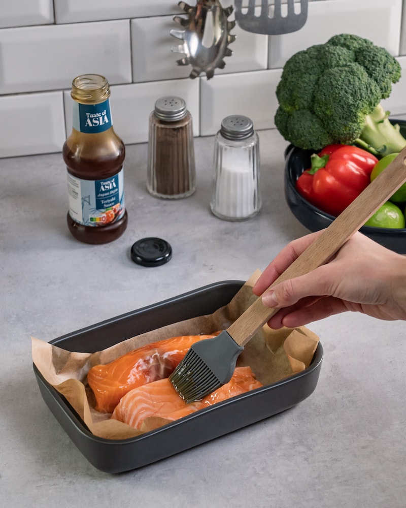 Dieses Bild zeigt wie der Lachs bepinselt wird.