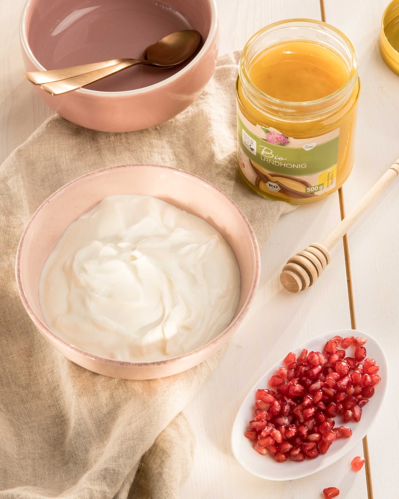 Dieses Bild zeigt Joghurt, Honig und Granatapfelkerne.