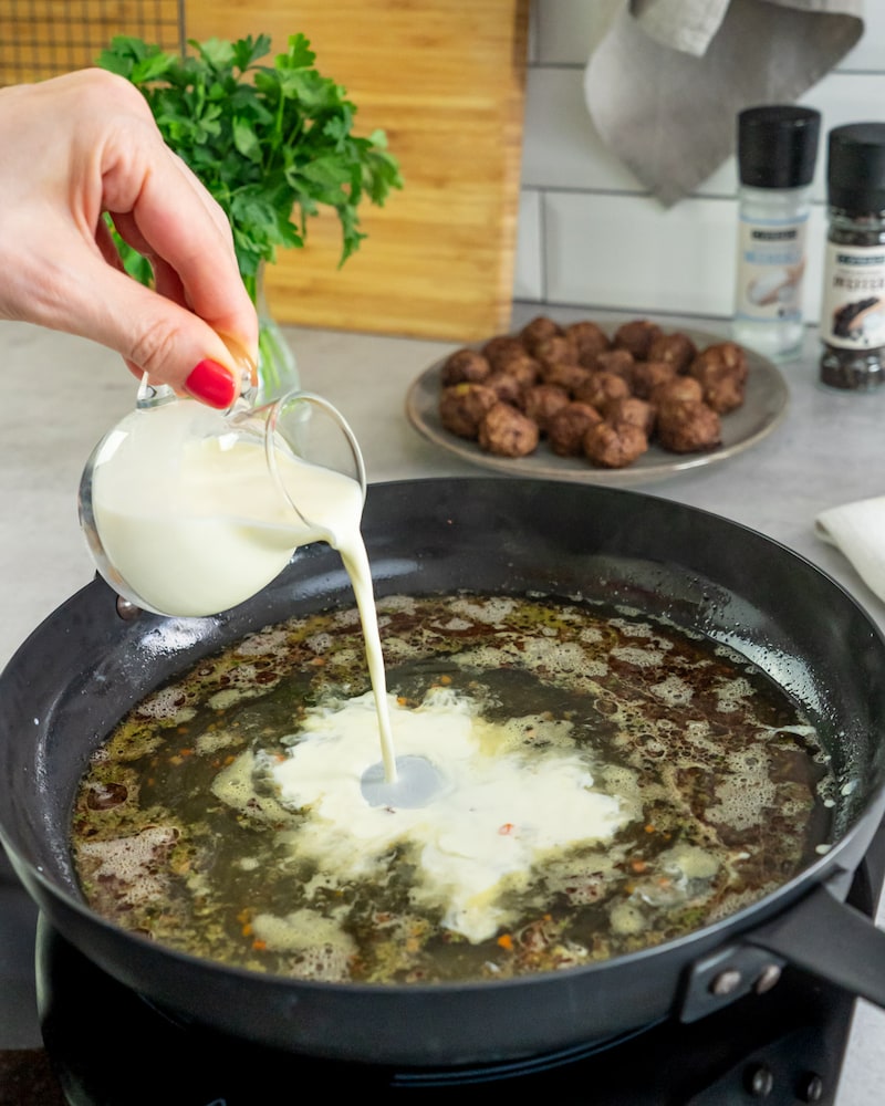 Das Bild zeigt wie die Jus mit Sahne abgelöscht wird.