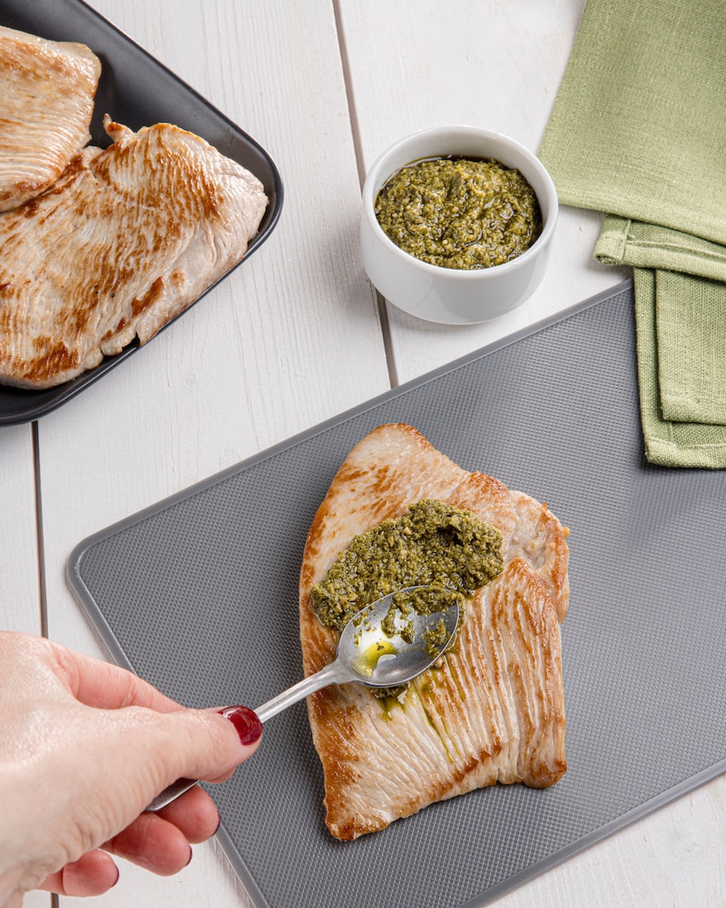 Dieses Bild zeigt wie das Putenschnitzel mit Pesto bestrichen wird.