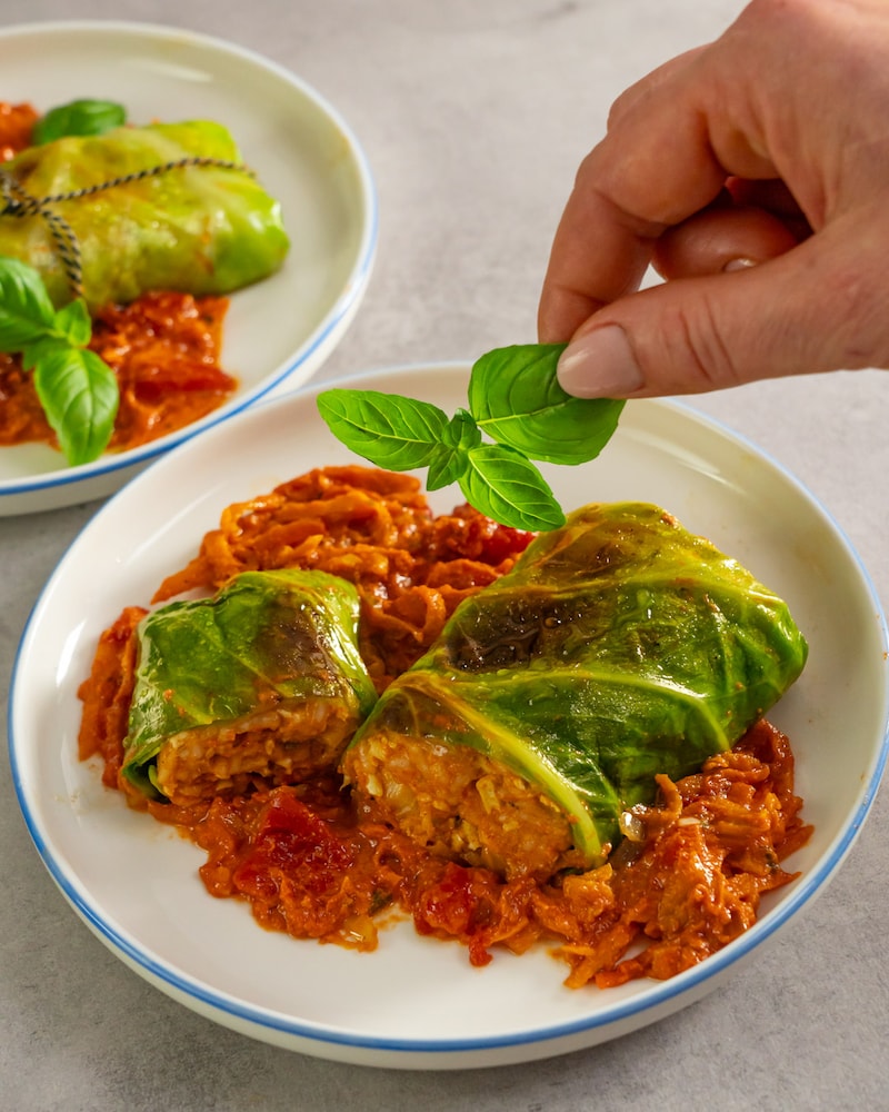 Dieses Bild zeigt wie die veganen Kohlrouladen mit Basilikum garniert werden.