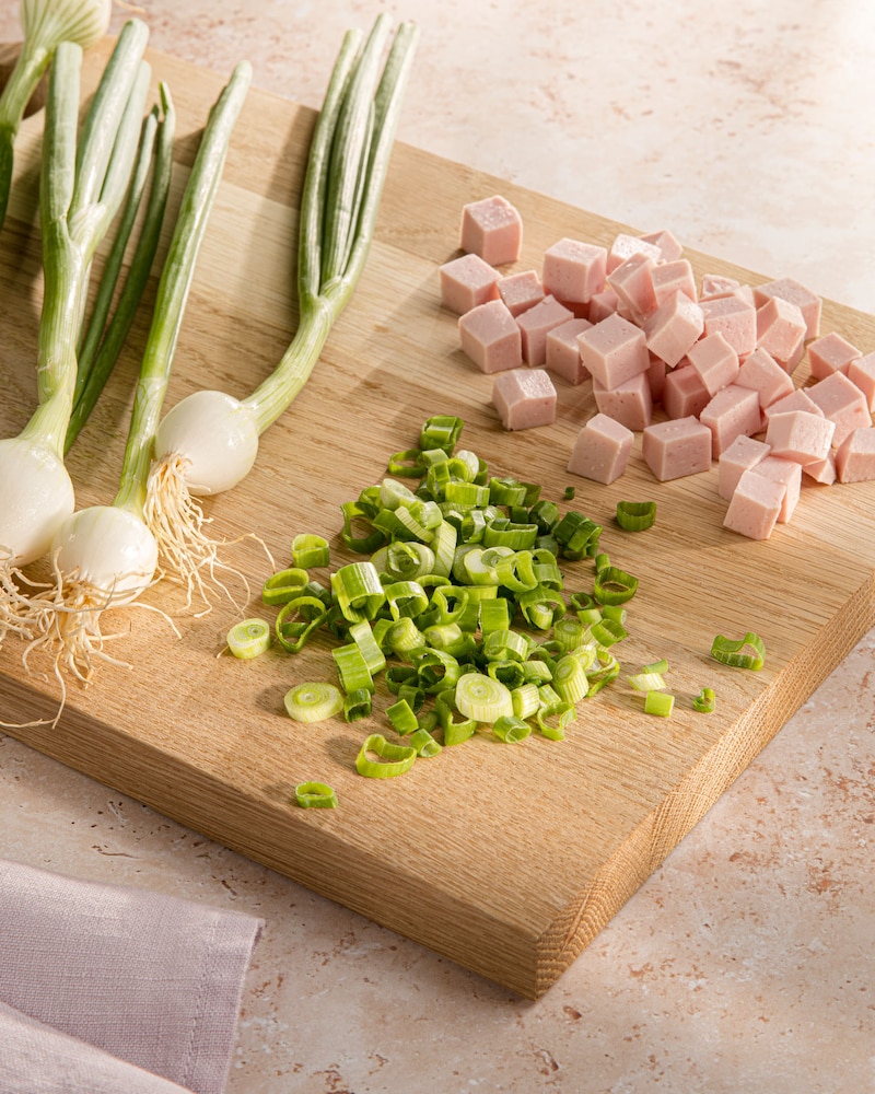 Das Bild zeigt die geschnittenen Frühlingszwiebeln und Wurst.