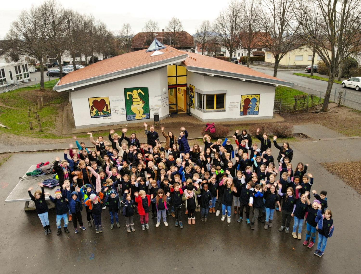 Kinder und Vereinsmitglieder winken laechelnd in die Kamera