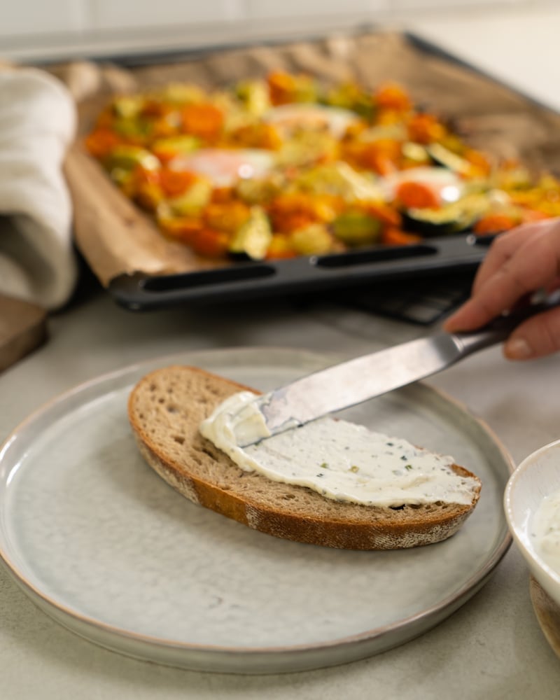 Auf diesem Bild siehst du wie ein Brot beschmiert wird.